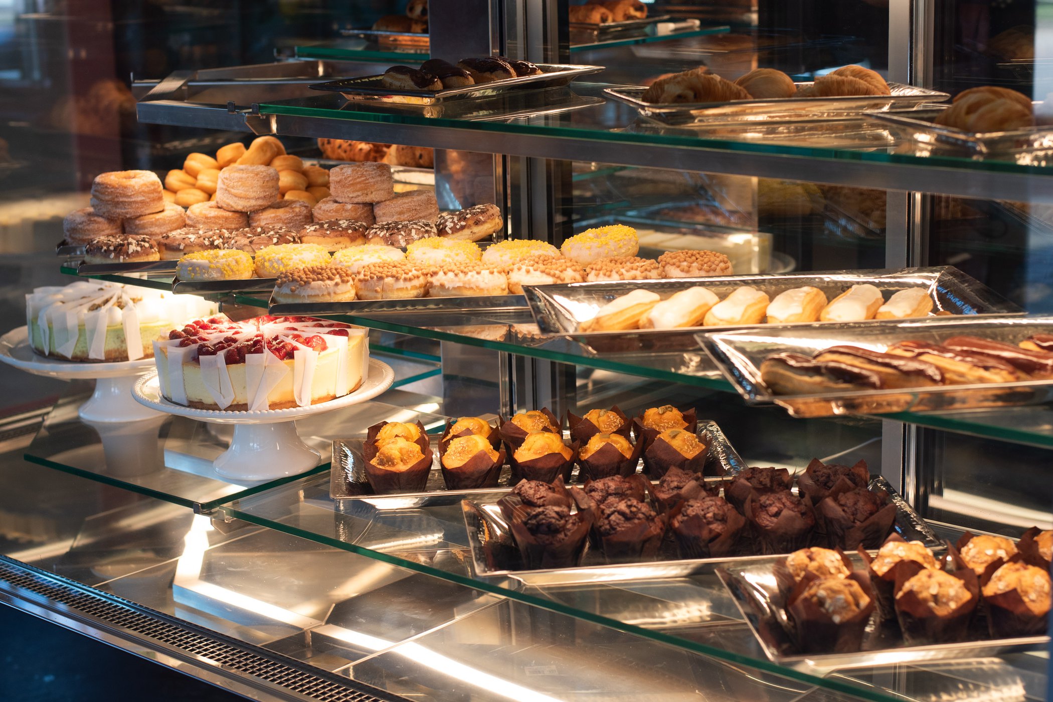 Display case with various baked goods including cookies, cakes, and pastries on glass shelves.